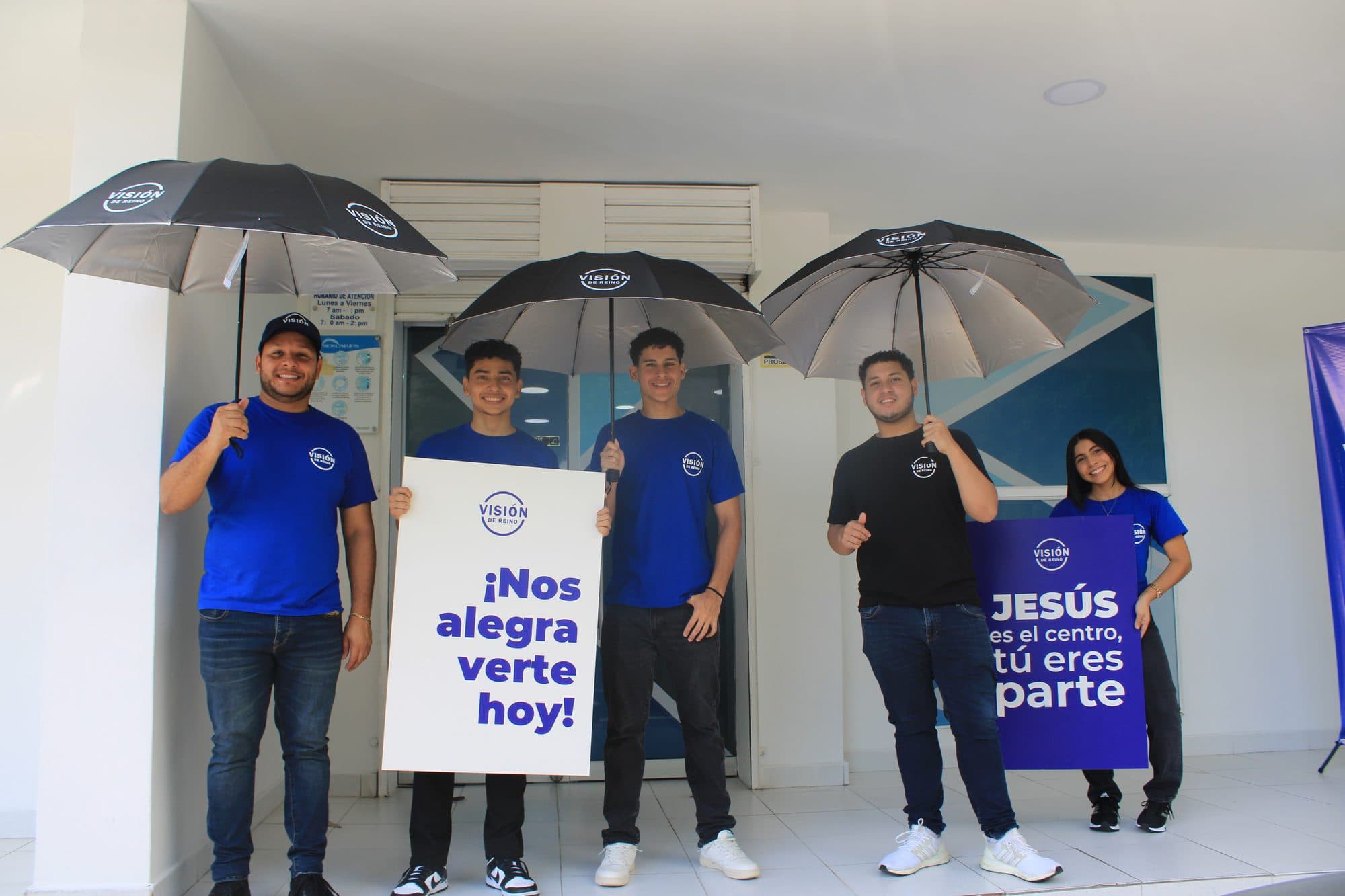 El equipo de bienvenida de Visión de Reino con un cartel que dice: ¡Nos alegra verte hoy!